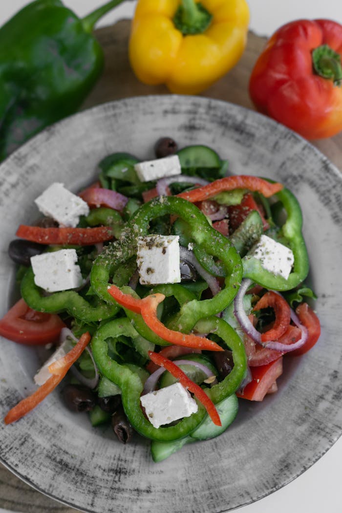 portfolio-03 A vibrant Greek salad with fresh bell peppers, feta cheese, and olives, served in a rustic bowl.