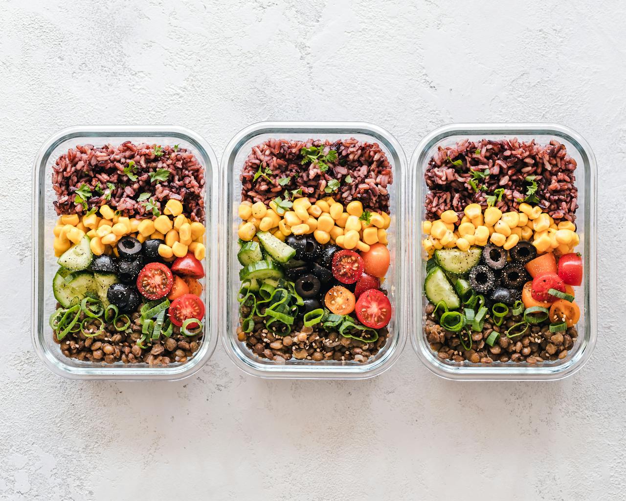 why-choose-us Colorful healthy meal prep with corn, olives, tomatoes, and lentils in glass containers. Perfect for mindful eating.